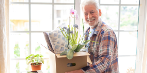Senior man holding box of possessions and smiling