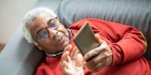 Senior man laying on couch and looking at his phone