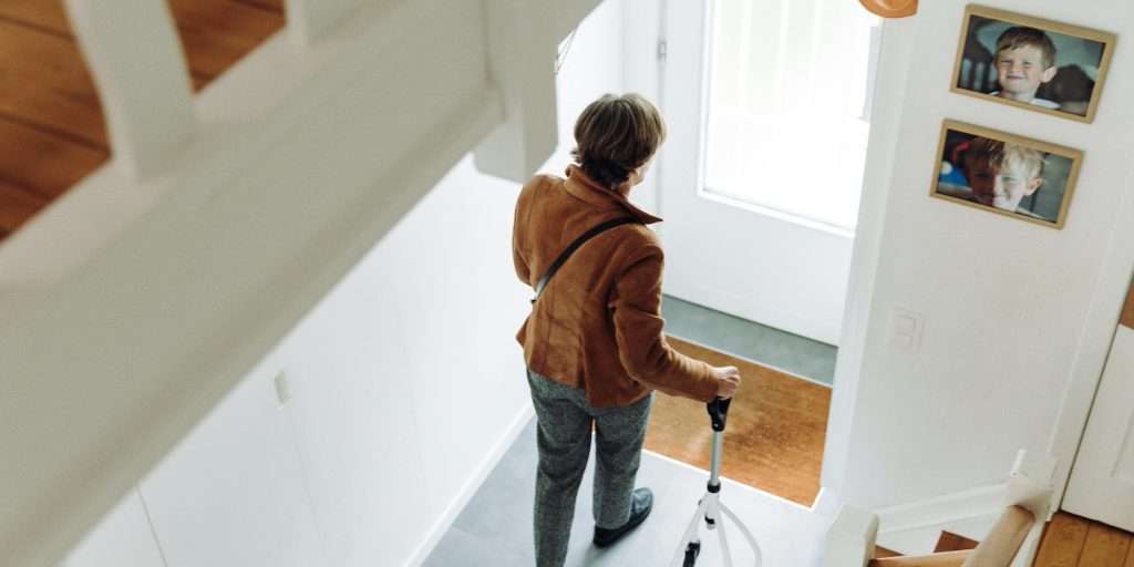 Senior woman walking towards front door using a walking aid