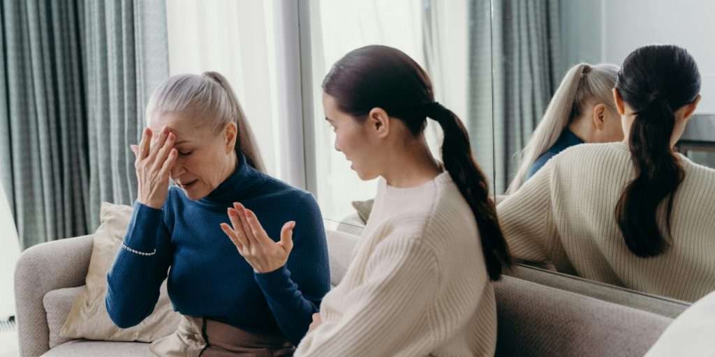 A touching moment of bonding between a mother and daughter sitting on a couch indoors.