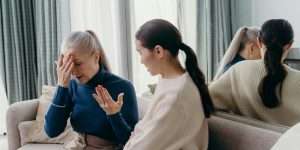A touching moment of bonding between a mother and daughter sitting on a couch indoors.
