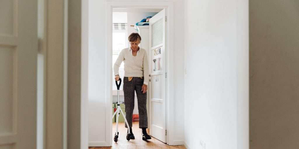 Older woman with a walker standing in the doorway of her home